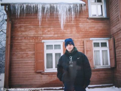 Boy in blue hat in front of red wooden house with icicles