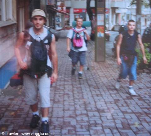Three young backpackers walking on a cobblestone city street