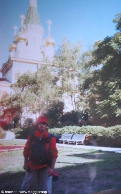 Backpacker in front of an Orthodox church with golden domes and crosses