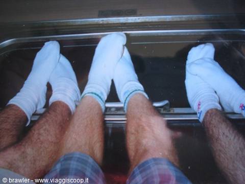 Three pairs of white-socked feet resting on the train window