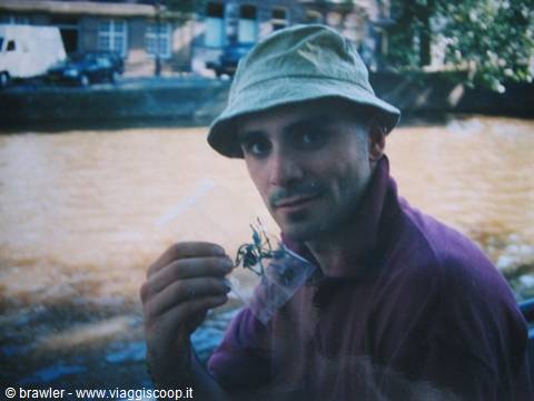 Man in bucket hat shows a small wrapped souvenir by a canal