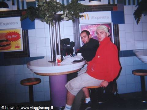 Two young men at a McDonald's table, fake plants and neon lights