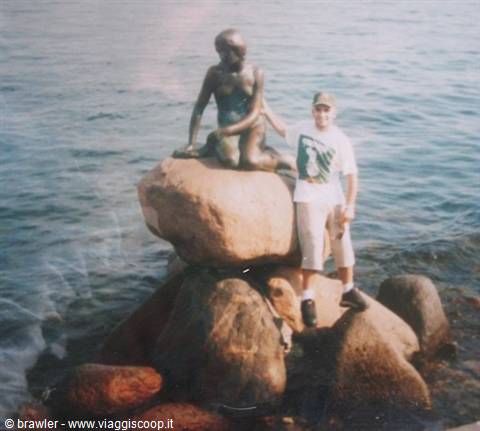 Tourist beside the bronze Little Mermaid statue of Copenhagen on the seaside rock