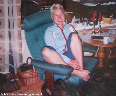 Smiling blonde woman sitting on green armchair in living room, next to candles