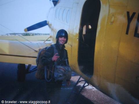Skydiver in gear beside a yellow aircraft on the airstrip