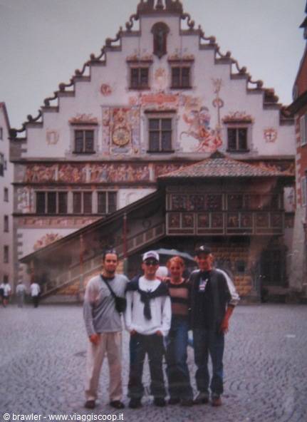 Four friends standing on cobblestones in front of Lindau's frescoed old town hall
