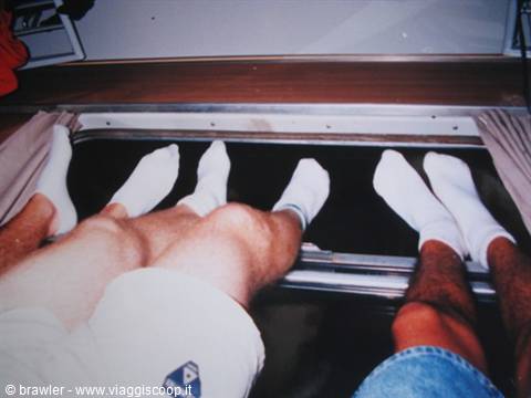 Two pairs of legs in white socks stretched over a boat porthole