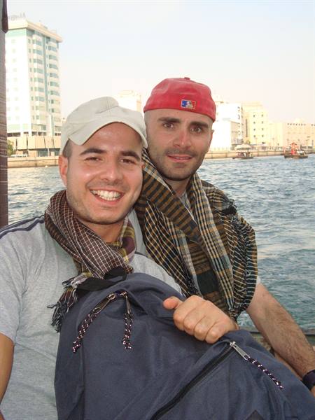 Two young travelers with scarves and backpack smile aboard a boat on Dubai Creek