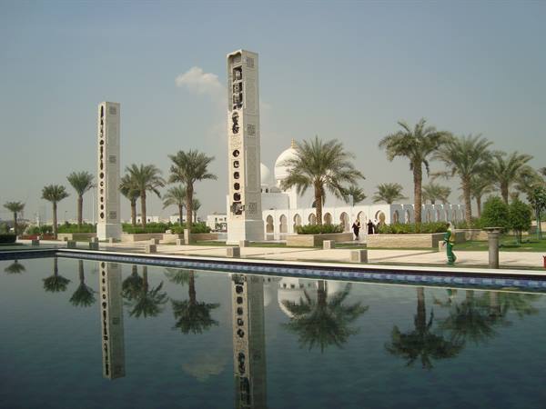 White minarets and palms reflect in the pool at Sheikh Zayed Mosque