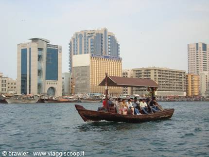 Wooden abra ferry carrying passengers across Dubai Creek past skyscrapers