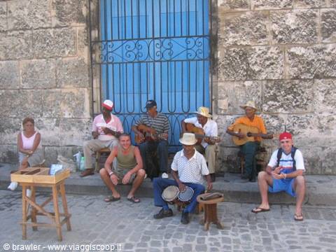 Street musicians with guitars and bongos in front of a blue window in Havana