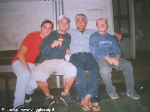 Four friends sitting on a bench, one holding a soda can, indoor light