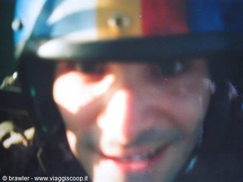 Smiling man wearing a colorful helmet, sunlight on his face, blurry shot