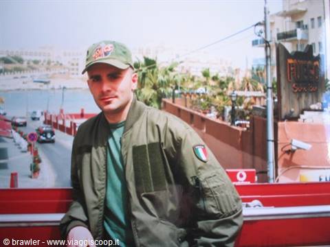 Man wearing military jacket with Italian flag patch beside streets and harbor