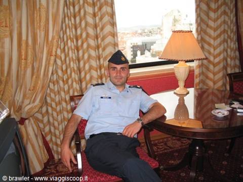 Man in light blue uniform and beret sitting beside a wooden table