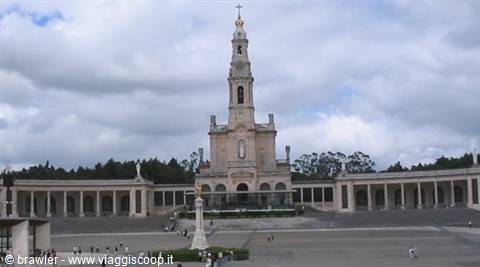 Sanctuary of Fatima: basilica with tall bell tower between colonnades, cloudy sky, few visitors