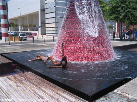 Children play in the water of the red cone fountain in Parque das Nações