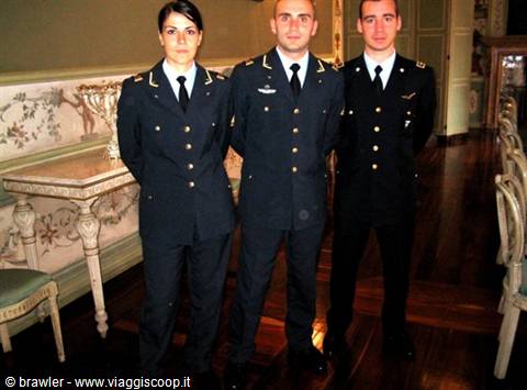 Three uniformed officers in blue with gold buttons inside a wood-floored hall