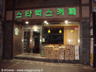 Green neon Starbucks sign in Seoul, cardboard boxes stacked under the window