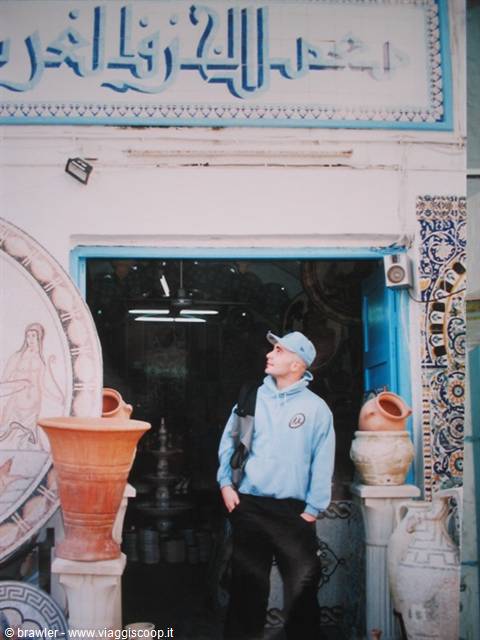 Young man in blue hoodie outside a pottery shop in Nabeul