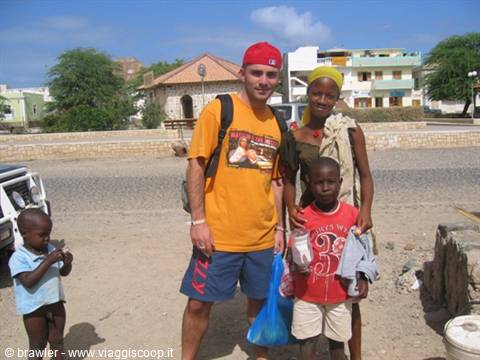 Tourist with local children on the sandy square of Santa Maria, colorful buildings, tropical light