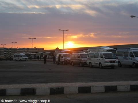 Sunrise over a parking lot with white minibuses and vans