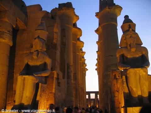 Illuminated pharaoh statues and columns at dusk in Luxor Temple