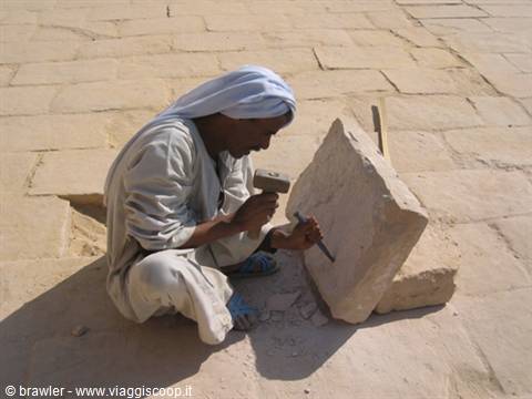 Worker in white turban carves a sandstone block with mallet and chisel