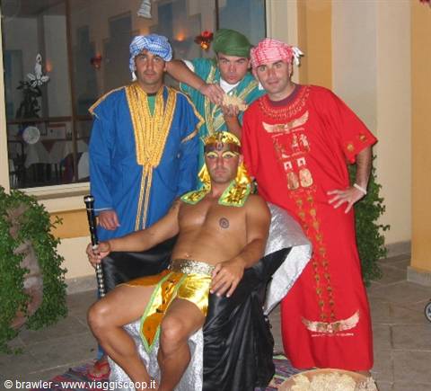 Man in pharaoh costume seated, friends in colorful robes and turbans, evening terrace