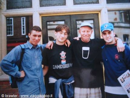 Four friends in t-shirts and caps posing in front of a glass door