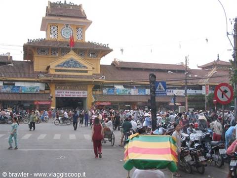 Cho Ben Thanh market: yellow clock tower entrance, crowded with scooters and pedestrians
