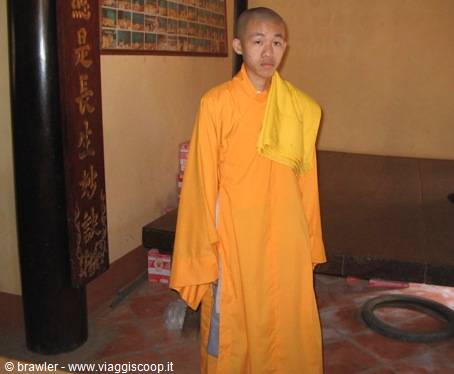 Young monk in orange robe inside a Buddhist temple hall