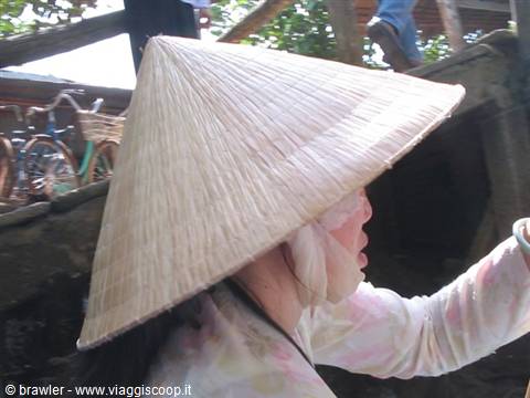 Woman wearing conical straw hat, bicycles in the background