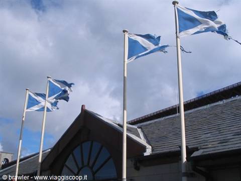 Torn Scottish saltire flags waving on poles above the slate roof