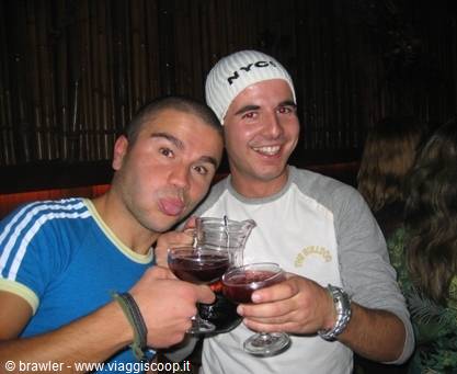 Two friends toast with red wine glasses in a dim bar