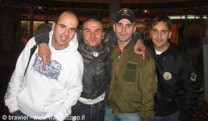 Four friends hugging and smiling at night, one making horn hand sign