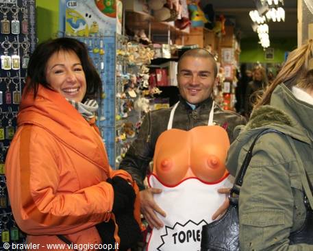 Woman in orange jacket and man wearing joke apron inside souvenir shop