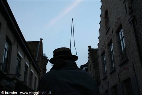 Man in straw hat among brick houses in Bruges, dusk light