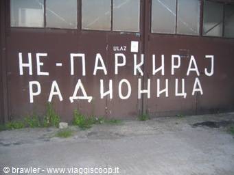 Cyrillic sign reading 'no parking' on the brown metal wall of a radio station