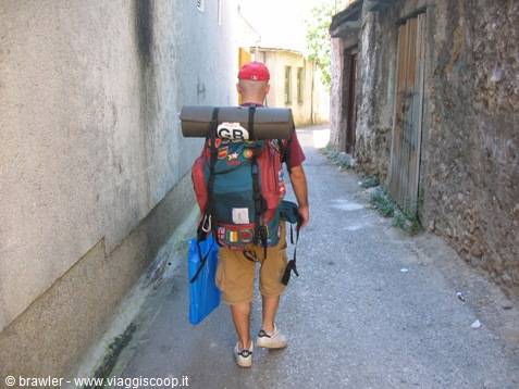 Backpacker with mat and red cap walking through a narrow old alley