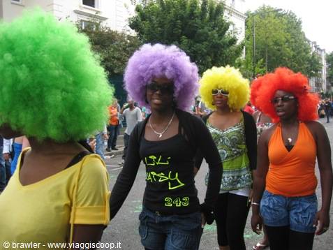 Women wearing colorful afro wigs parading along a street among the crowd