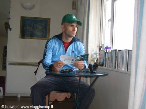 Man in green cap reading ticket at small table by the window