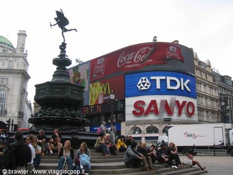 Tourists sitting on the steps beneath the Eros statue at Piccadilly Circus, London