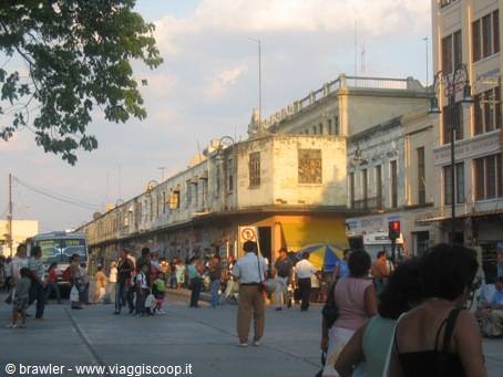 Passengers wait for the bus beside weathered old buildings