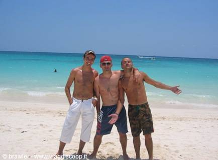 Three friends smiling on white sand beach with turquoise sea