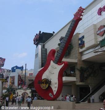 Giant red guitar statue in front of the Hard Rock store, tourists walking below