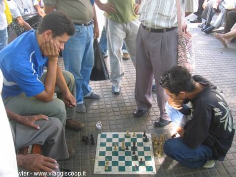 Two concentrated men playing chess on a board placed on the ground