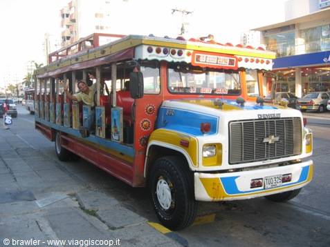 Colorful chiva party bus with waving passengers, Cartagena sign visible