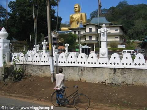 Man with bicycle in front of the giant golden Buddha at Dambulla