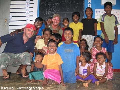 Two tourists with a group of smiling children in a school classroom